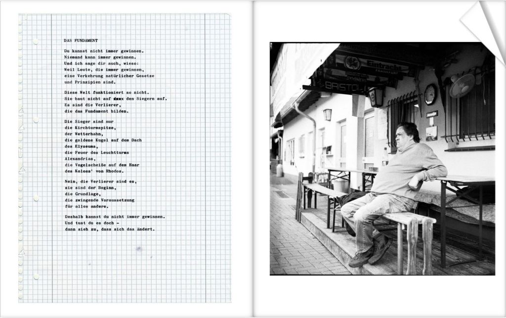 A black and white photograph of a man sitting on a bench outside a building, with a relaxed posture and a thoughtful expression.